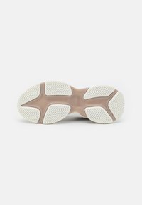 Suela de zapato con goma blanca texturizada y patrones en zigzag, destacada por una entresuela marrón claro. Bordes de superficie suaves, diseño duradero.