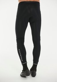 Svarta atletiska leggings med en tight passform, med en vadderad bakdel och en 'ENDURANCE'-logotyp i vitt längs vänster ben. Slät textur.