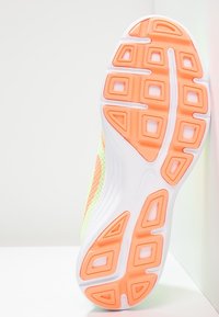 Semelle de chaussure avec un design texturé présentant des motifs rectangulaires et triangulaires. Les couleurs incluent des accents blancs, orange et verts.