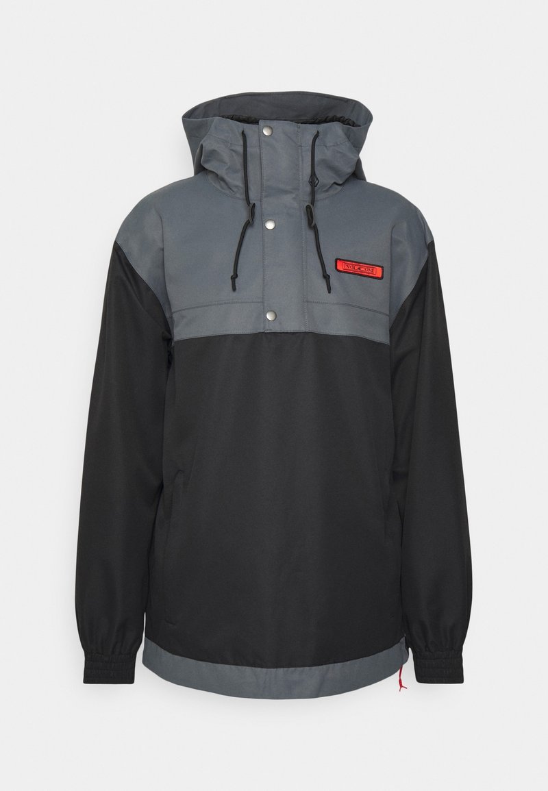 Mustat ja harmaat anorakki-takki, jossa on puolivetoketju, säädettävä huppu ja joustavat hihansuut. Rintalaskoksessa on punainen logo-patch ja napit.