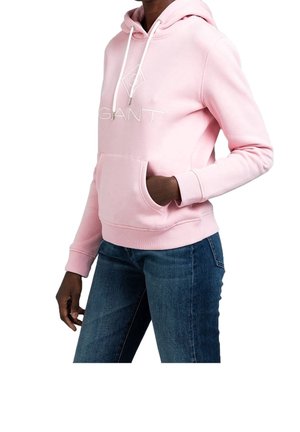 Sweatshirt à capuche rose avec cordons, poche avant et logo 'GANT' en blanc. Tissu doux et design ajusté, associé à un jean bleu.