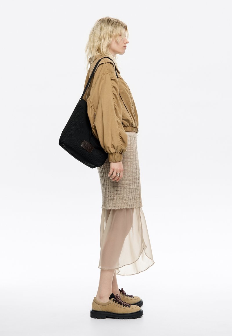 Bežinė bomber tipo striukė, megzta bežinė sijonas su permatomu sluoksniu, juoda hobo tipo rankinė ir bežinės spalvos batai su tamsiomis raišteliais ir storomis padais.