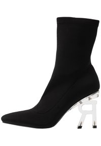 Bottine noire de style chaussette à bout pointu, avec un talon bloc transparent en forme de lettre "R" à l'envers.