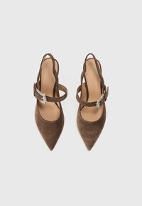 Καφέ γόβες από σουέτ με ψηλό τακούνι και μυτερή μύτη. Διαθέτουν λουράκι στον αστράγαλο και διακοσμητικό αγκράφα με στρας.