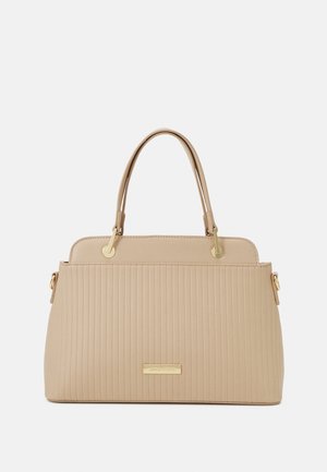 Sac à main beige avec texture côtelée verticale, doubles poignées, ferrures dorées et une petite plaque de marque rectangulaire à l'avant.