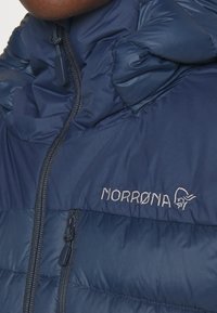 Norrøna tamnoplava podstavljena jakna s patentnim zatvaračem, visokim ovratnikom i izvezenim logotipom, izrađena od glatkog, laganog materijala.