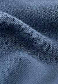 Tessuto lavorato a maglia blu che mostra un motivo testurizzato con fili sottili e grossi, caratterizzato da una superficie morbida e leggermente pelosa.