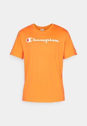 Orange bomulds t-shirt med rund halsudskæring og korte ærmer. Har hvid "Champion" tekst hen over forsiden. Glat tekstur.