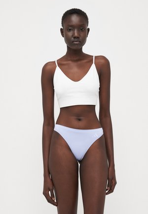 White cropped tank top with thin straps, paired with light purple bikini briefs featuring a subtle logo. Smooth fabric, minimalist design.