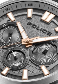 Srebrny zegarek metalowy z teksturowaną szaro-skalową tarczą, różowymi złotymi akcentami, licznymi podtarcza i wyraźnymi białymi znacznikami godzin, z logo "POLICE".