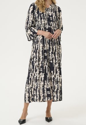 Sukienka maxi w kolorze granatowym i kremowym z pionowym abstrakcyjnym wzorem. Posiada plisowane detale i długie rękawy. Gładka tkanina, luźny krój, długość za kolano.
