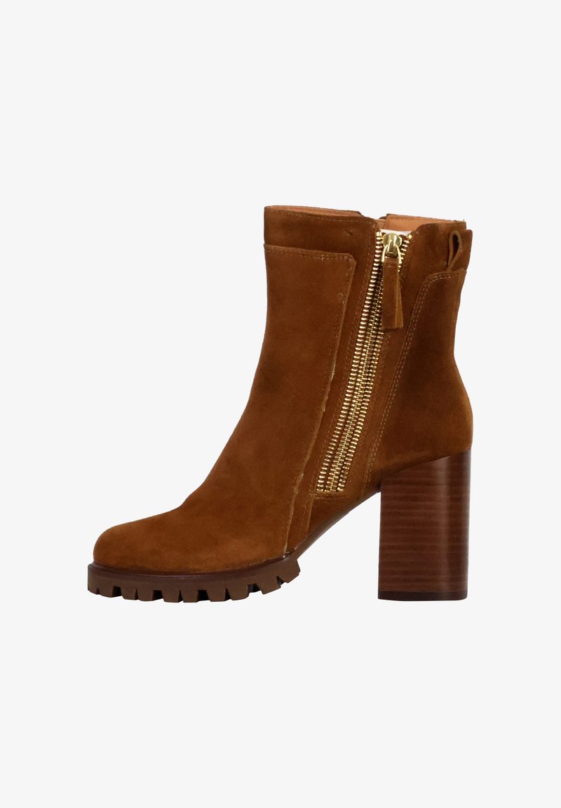Stivale alla caviglia in suede marrone con tacco in legno chunky e zip laterale. Suola testurizzata per una presa sicura e finitura liscia sulla parte superiore.