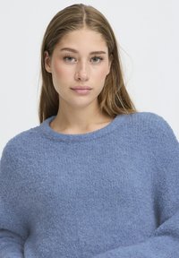 Maglione blu testurizzato con scollatura rotonda e maniche lunghe, caratterizzato da un aspetto morbido e peloso e una vestibilità casual.