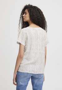 Blusa a maniche corte in crema con strisce verticali multicolori. Tessuto morbido, vestibilità rilassata e scollo a barca.
