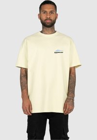 Lichtgele oversized t-shirt van katoen, met een grafisch logo in zwart en blauw op de linkerkant van de borst, korte mouwen en een klassieke ronde hals.