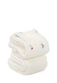 Białe puszyste ręczniki ułożone w stos, z małymi czerwonymi i niebieskimi wzorami. Miękka tekstura i puszyste wykończenie, idealne do osuszania i komfortu.