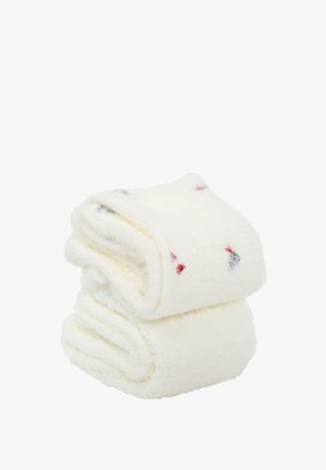 Toallas blancas esponjosas apiladas, con pequeños patrones rojos y azules. Textura suave y sensación mullida, ideales para secar y para el confort.