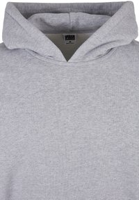 Sweat à capuche gris clair avec capuche repliée et étiquette visible indiquant "Urban Classics M Made in China" à l'intérieur du col.