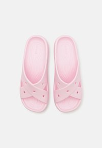 Paire de sandales plates rose clair avec des brides croisées comprenant des trous de ventilation, des semelles texturées et un design facile à enfiler.