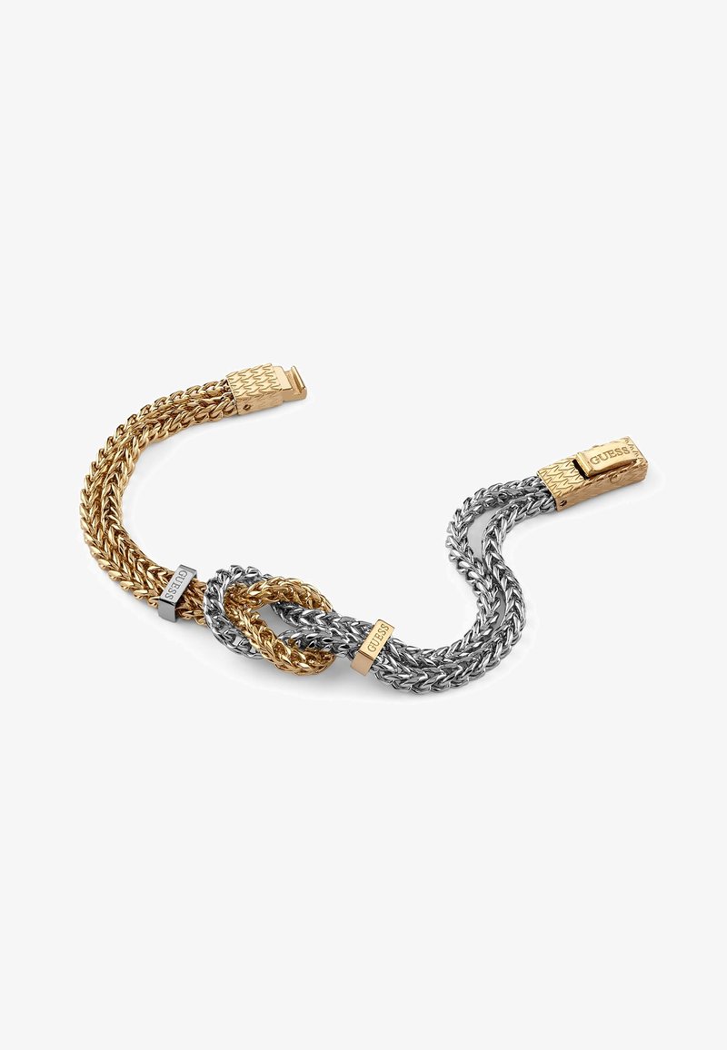 Bracciale a catena intrecciata in oro e argento caratterizzato da un design a spirale, anelli intrecciati e chiusure brandizzate con la scritta "GUESS" incisa.
