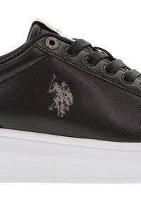 Sneaker in pelle nera con una superficie liscia, dotato di una suola in gomma bianca e un accento di logo argentato sul lato. Sei fori per i lacci.