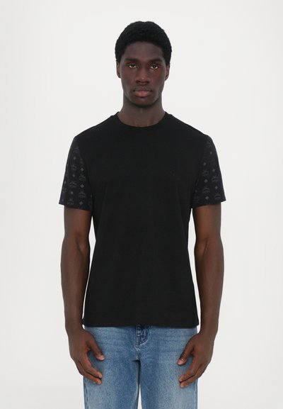 Zwarte crew-neck t-shirt met gemusterde zwarte korte mouwen, voorzien van een subtiele logo op de borst, gecombineerd met blauwe jeans.