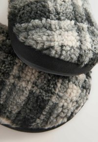 Tmavošedé a krémové papuče so vzorom, s textúrovaným, plyšovým povrchom a hladkou čiernou podrážkou. Okrúhly tvar s mäkkým a pohodlným materiálom.