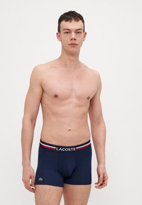 Caleçons boxers bleu marine avec une taille élastique de marque ornée de rayures rouges et blanches. Fabriqués en tissu doux et extensible pour le confort.