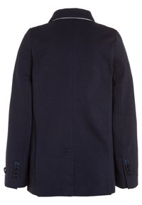 Tmavě modrý kabát se strukturovaným designem, s klopovým límcem, bílým dekorativním prošíváním a manžetami se čtyřmi knoflíky.