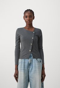 Cardigan long à manches longues gris côtelé avec un décolleté en V et cinq boutons ronds à l'avant, porté sur un jean large bleu clair.