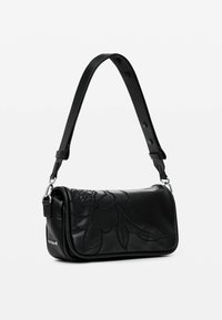 Sac à main en cuir noir avec motif floral en relief, forme rectangulaire, bandoulière réglable et accents en métal argenté.