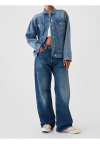 Veste en denim bleu moyen à manches longues, fermeture à boutons sur le devant, deux poches poitrine, et jean large assorti avec texture délavée.