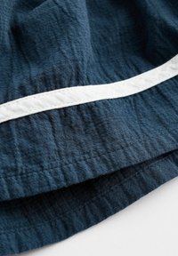 Tissu bleu marine avec une finition texturée présentant une bande horizontale blanche au centre. Matériau doux et léger.