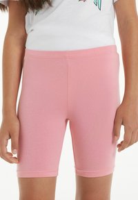 Růžové strečové šortky s těsným střihem, vyrobené z jemné látky. Mají hladkou strukturu a pas s minimálními švy.