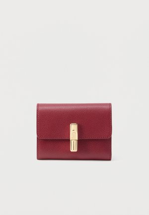 Μικρό πορτοφόλι από υφή σκληρού κόκκινου δέρματος με ορθογώνια χρυσή πόρπη σε απλό ανοιχτό φόντο.
