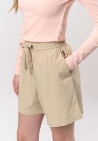 Bézs rövidnadrág rugalmas derékpánttal és húzózsinórral, oldalzsebekkel és egy kis hímzett részlettel. Puha, könnyű anyag.