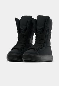 Juodas paminkštintas žieminis botas su aukštu auliuku, tekstūruota medžiaga, apvaliu pirštu ir plokščiu guminiu padu. Yra juodi raišteliai ir logotipo detalė.