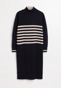 Svart långärmad stickad klänning med beige horisontella ränder över bröstet och ärmarna, med en hög ribbad halsringning.