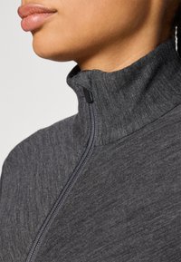 Gray high-neck zip-up top with a textured fabric, featuring a half-zip closure and subtle stitching details along the seams.