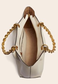 Sac à main en cuir blanc avec une surface texturée, des anses en chaîne torsadée dorée et une fermeture éclair. L'intérieur est beige clair avec une finition lisse.