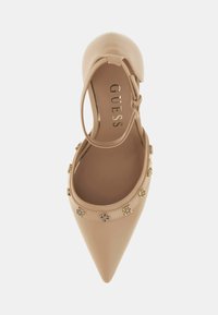 Beżowy, skórzany but na wysokim obcasie z zaostrzonym noskiem, paskiem wokół kostki oraz złotymi ozdobami wokół otworu. Płaska, gładka wkładka wewnętrzna.