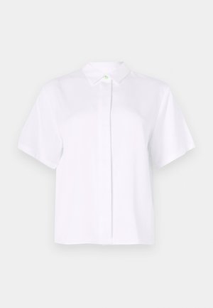 Kortermet hvit skjorte laget av glatt stoff, med spiss krage og en knappestolpe med en grønn detaljknapp.