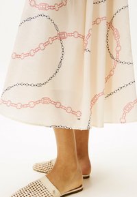 Lysebeige nederdel med rødt og sort kædemønster. Kompletteres af vævede beige slip-on sko med bred rem.