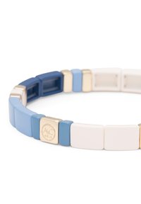 Pulsera de silicona con segmentos rectangulares en azul marino, azul claro, blanco y dorado. Presenta un emblema dorado con "A&C Oslo" inscrito.