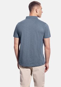 Mörkblå polo t-shirt för män, kort ärm, strukturerad tyg, kontrastsömmar, klassisk krage, kombinerad med ljusa byxor.