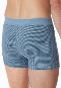 Blå mönstrade kalsonger med en texturerad diamantdesign och en mjuk elastisk midja, som visar en åtsittande passform och en len tyg.