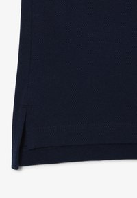 Navy-paita, jossa on sivuhaalareita, teksturoitu kangas ja ommellut reunat. Materiaali vaikuttaa kestävältä ja hengittävältä.