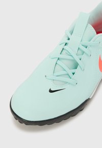 Baskets de sport bleu clair avec une surface texturée, logo Nike noir et accents rose. Elles sont dotées de lacets et d'une semelle en caoutchouc pour une meilleure adhérence.