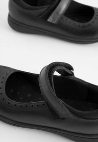 Pantofi Mary Jane din piele neagră, cu vârful rotunjit, detalii perforate și o curea centrală cu Velcro pentru o potrivire sigură.
