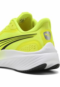 Scarpa da corsa gialla brillante con tomaia in rete, dettaglio a striscia nera, collo imbottito e suola bianca ammortizzata. Presenta il logo Puma sul tallone.